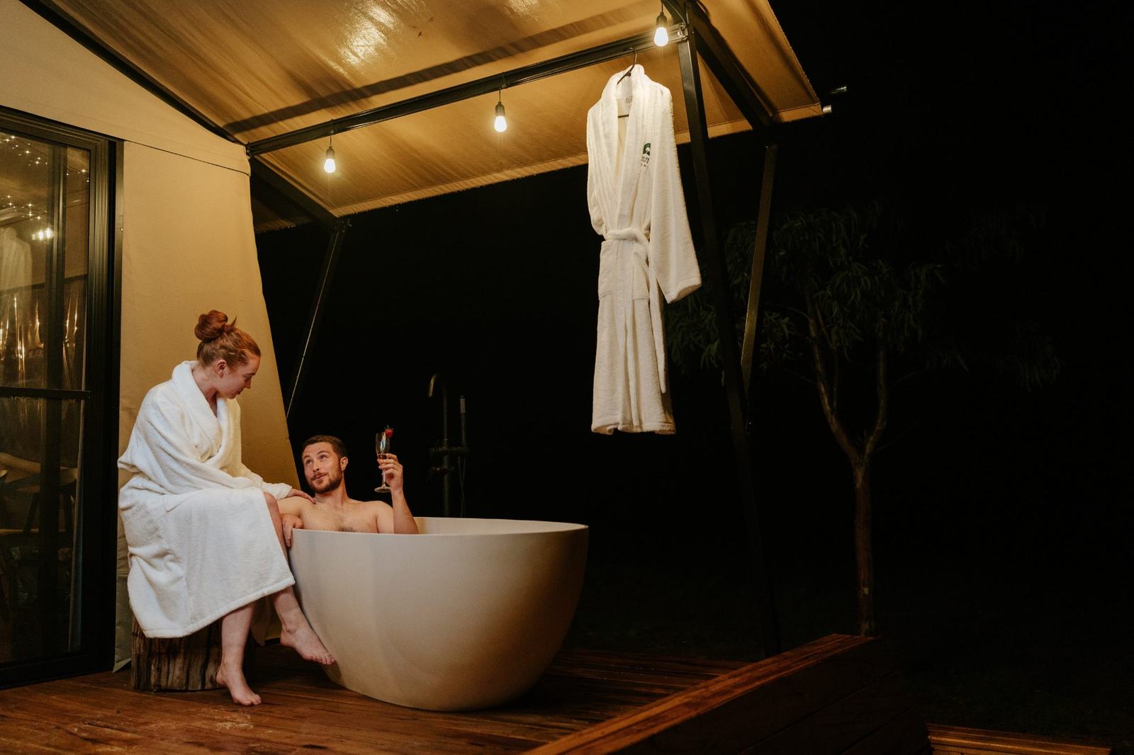 The outdoor bath on the deck at dusk, tent lit behind