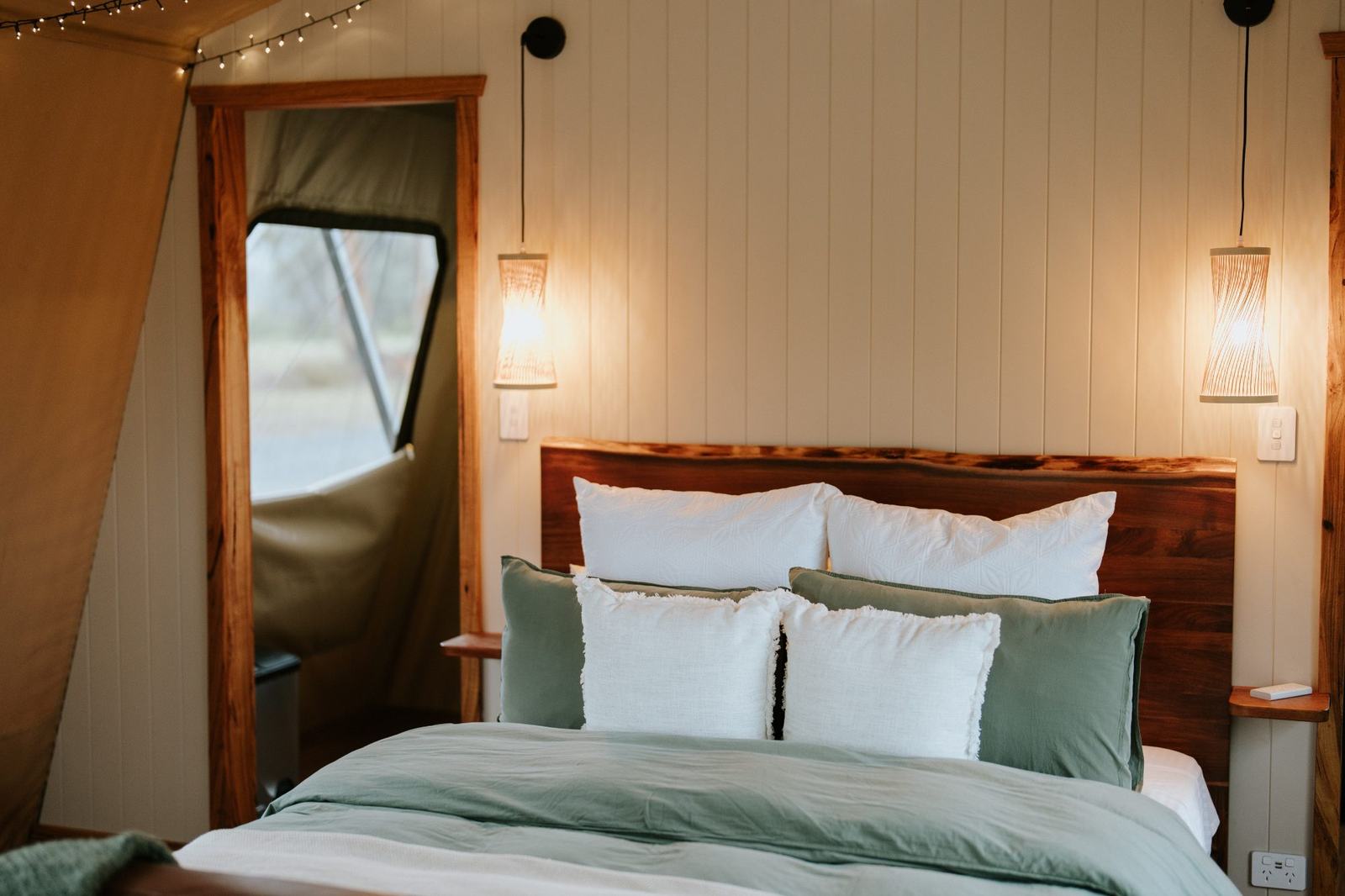 A cosy queen bed wrapped in fairy light