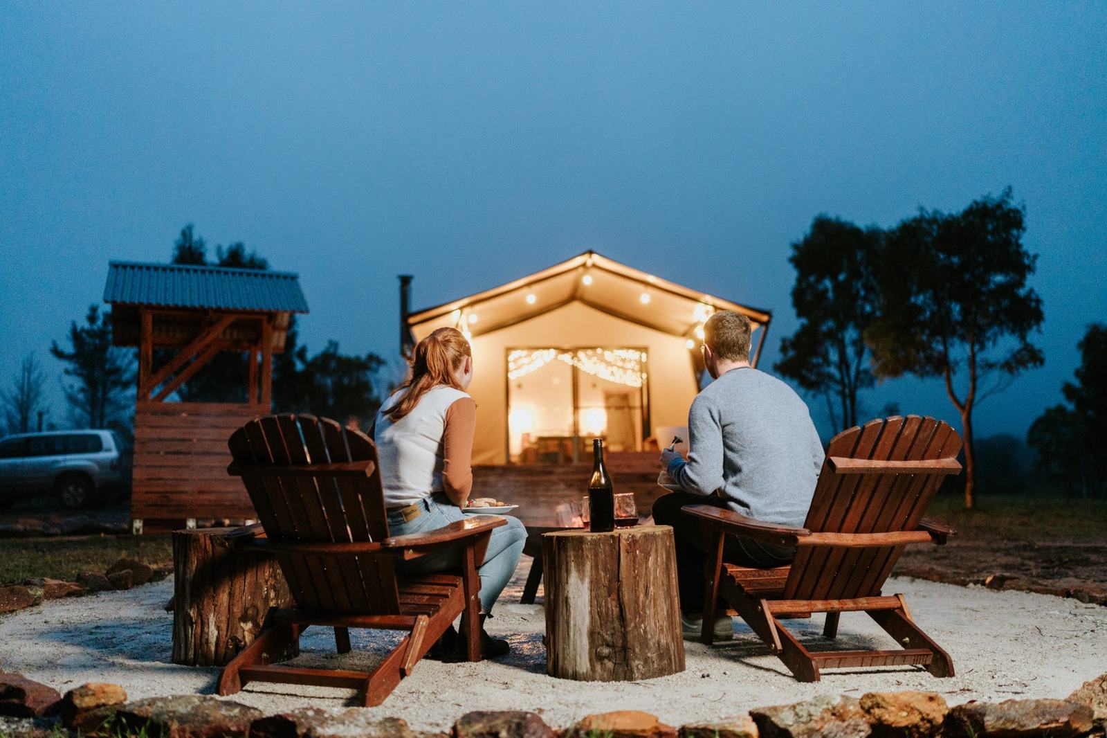 Fireside seating with the tent glowing at blue hour