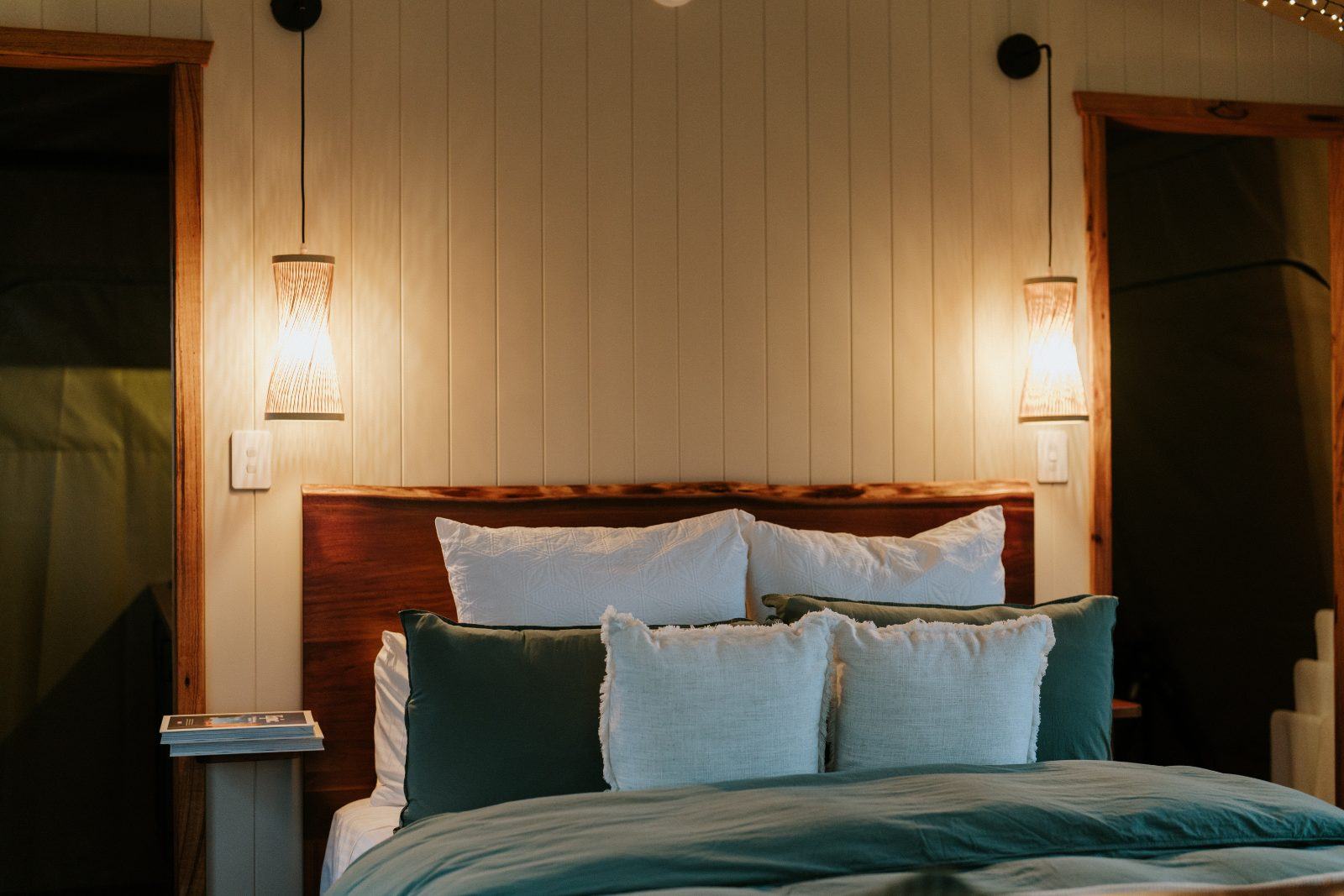 Queen bed lit by wall sconces