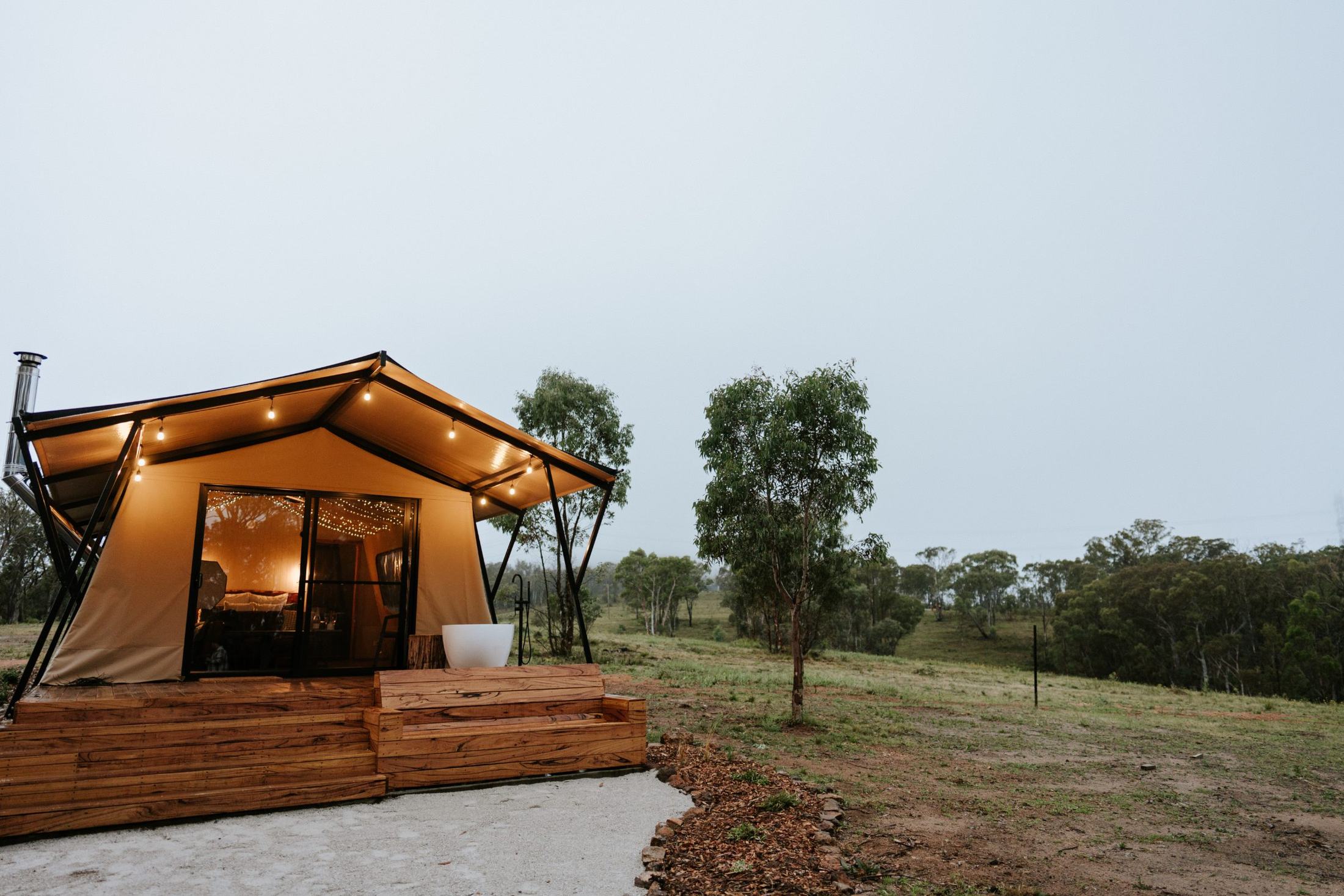Safari tent glowing at dusk over the Capertee Valley bush