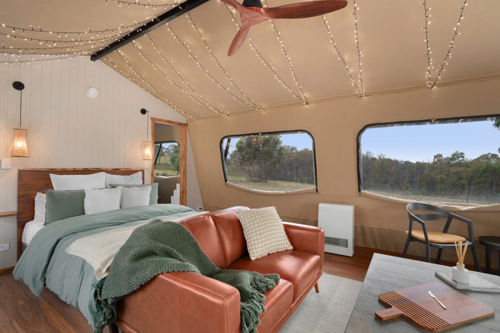 Luxury glamping tent interior, queen bed, leather sofa, warm light