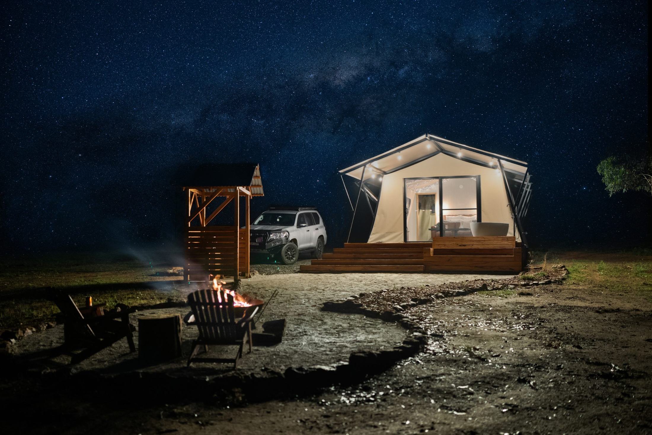 The lit tent beneath a sky full of stars